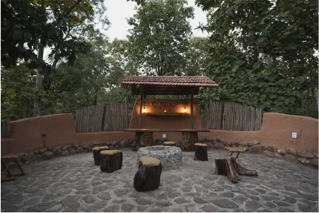 The bonfire circle with log stools under a lit wooden canopy